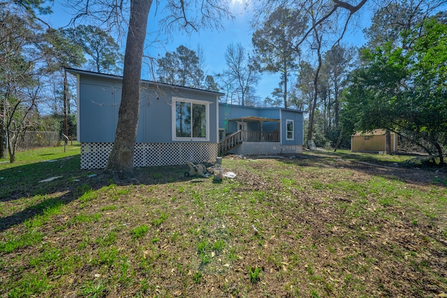 back of property featuring a yard and an outdoor structure