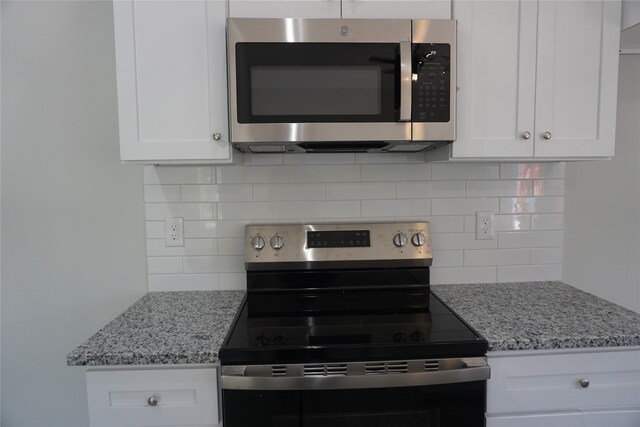 kitchen with decorative backsplash, light stone countertops, white cabinets, and appliances with stainless steel finishes