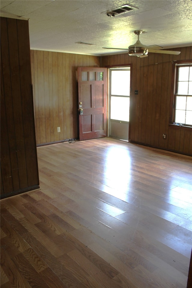 empty room with wood walls, wood-type flooring, and a textured ceiling