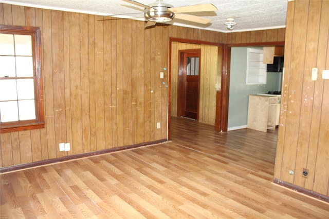 empty room featuring wood walls, light hardwood / wood-style flooring, and ceiling fan