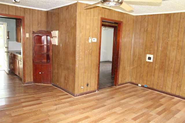 unfurnished room featuring wood walls, ceiling fan, and light wood-type flooring