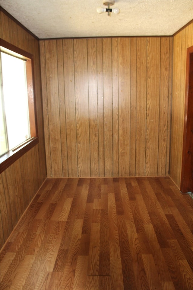 spare room featuring wooden walls, a textured ceiling, and hardwood / wood-style floors