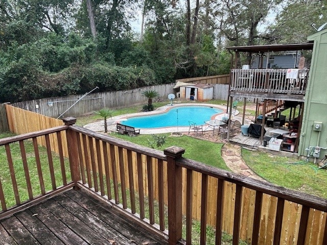 view of swimming pool featuring a lawn, a storage unit, and a deck