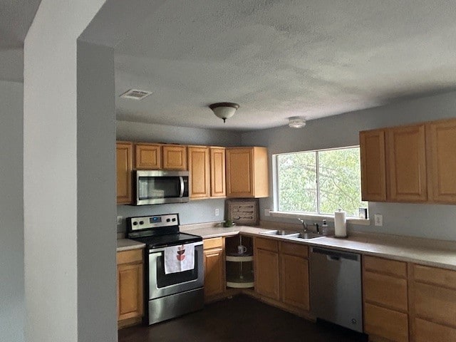 kitchen featuring a textured ceiling, stainless steel appliances, and sink