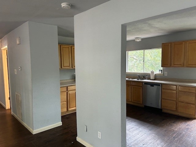 kitchen with dark hardwood / wood-style flooring, stainless steel dishwasher, and sink