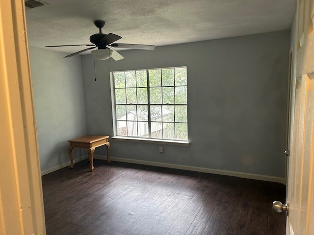 spare room featuring ceiling fan, dark hardwood / wood-style flooring, and a textured ceiling