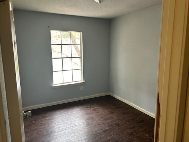 unfurnished room with dark hardwood / wood-style floors and a textured ceiling