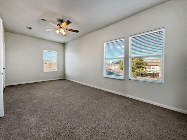 empty room with ceiling fan and dark colored carpet