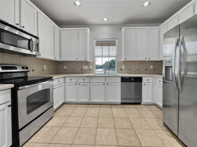 kitchen featuring white cabinetry, stainless steel appliances, light tile patterned floors, and backsplash