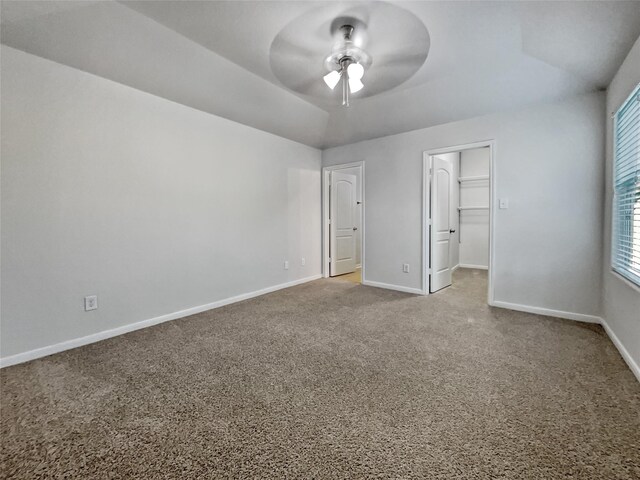 unfurnished bedroom with a closet, light carpet, a walk in closet, and ceiling fan