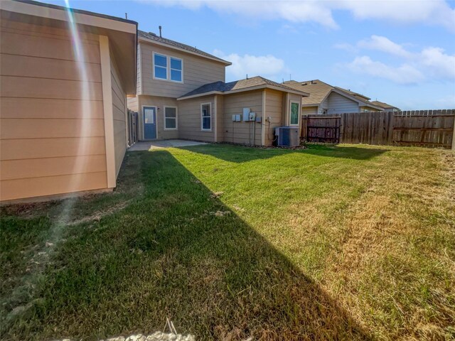 rear view of property with central AC and a yard