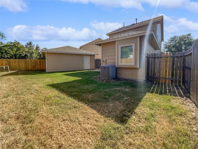 rear view of house with central AC unit and a yard