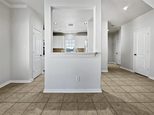 kitchen featuring white cabinets, stainless steel refrigerator, light tile patterned floors, and kitchen peninsula