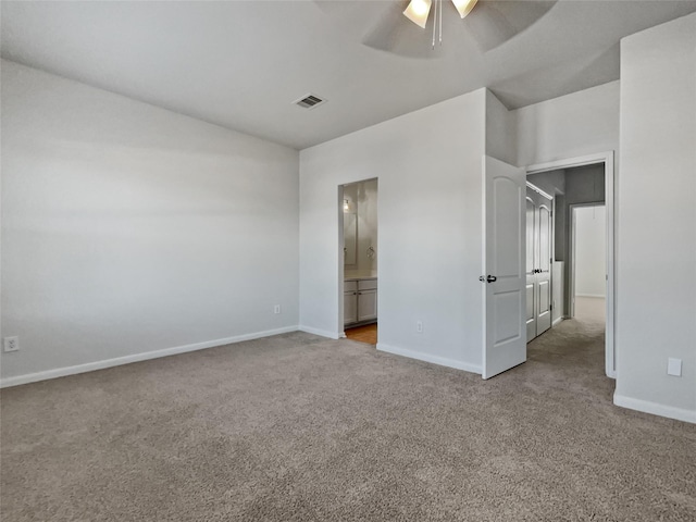 unfurnished bedroom featuring ensuite bathroom, light colored carpet, and ceiling fan