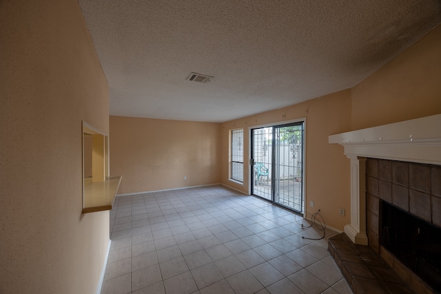 unfurnished living room with a textured ceiling, a tile fireplace, and light tile patterned floors