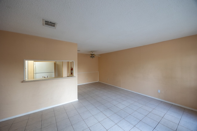 empty room with a textured ceiling, light tile patterned floors, and ceiling fan