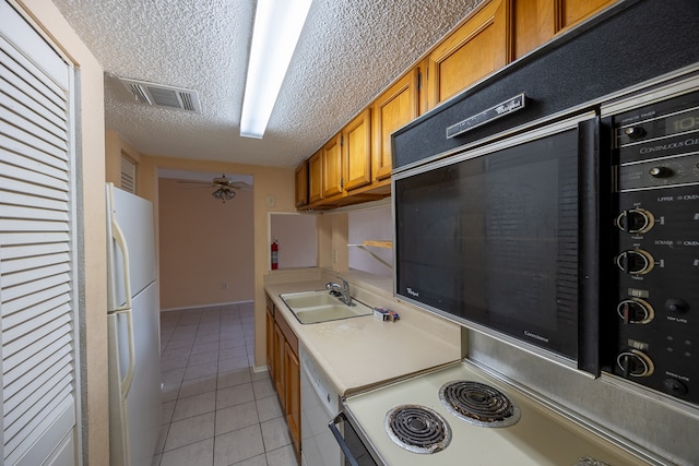 kitchen featuring white appliances, light tile patterned floors, a textured ceiling, ceiling fan, and sink