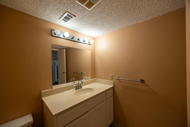 bathroom with vanity, a textured ceiling, and toilet