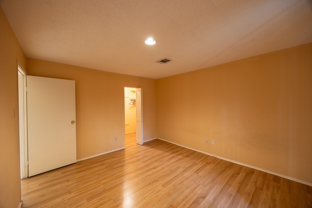 spare room featuring a textured ceiling and light wood-type flooring