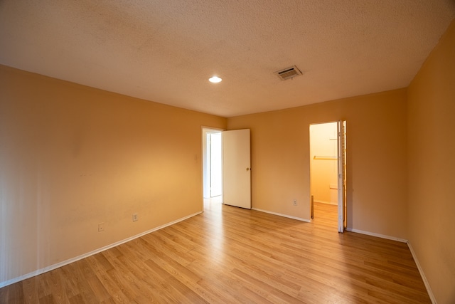 unfurnished room featuring light wood-type flooring and a textured ceiling