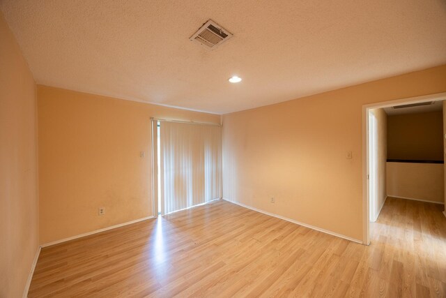 spare room with a textured ceiling and light hardwood / wood-style flooring