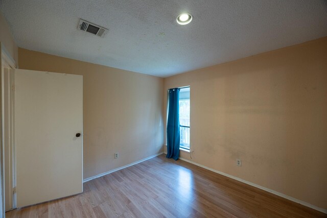 unfurnished room featuring light hardwood / wood-style floors and a textured ceiling