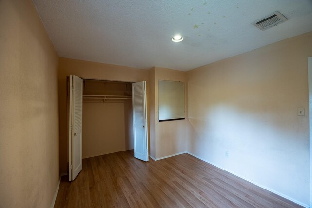 unfurnished bedroom featuring light hardwood / wood-style floors, a closet, and a textured ceiling