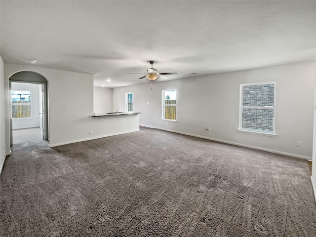 carpeted empty room with ceiling fan and plenty of natural light