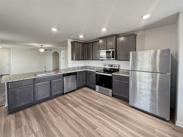 kitchen with appliances with stainless steel finishes, sink, light hardwood / wood-style floors, kitchen peninsula, and dark brown cabinets