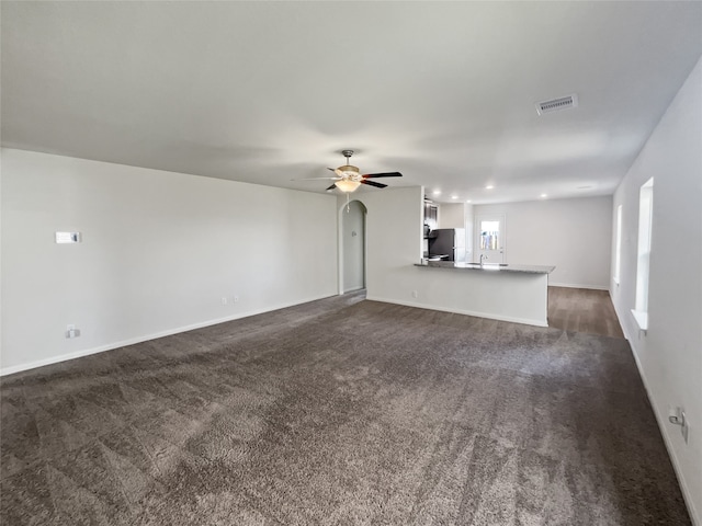 unfurnished living room featuring dark colored carpet and ceiling fan