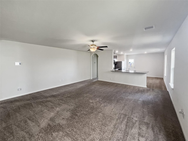 unfurnished living room with dark carpet and ceiling fan