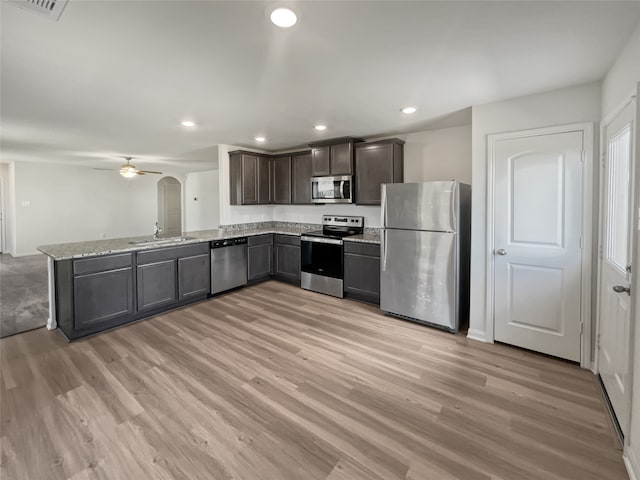 kitchen with ceiling fan, stainless steel appliances, sink, light hardwood / wood-style flooring, and kitchen peninsula