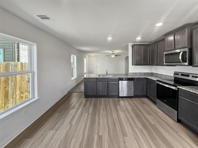 kitchen featuring appliances with stainless steel finishes, sink, kitchen peninsula, light hardwood / wood-style floors, and ceiling fan