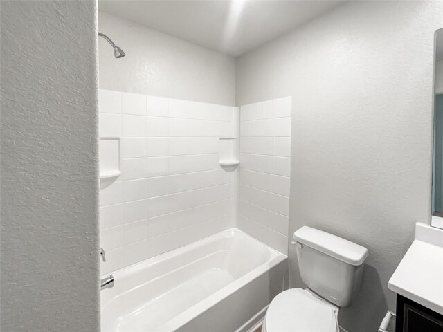 full bathroom featuring vanity, tiled shower / bath, and toilet