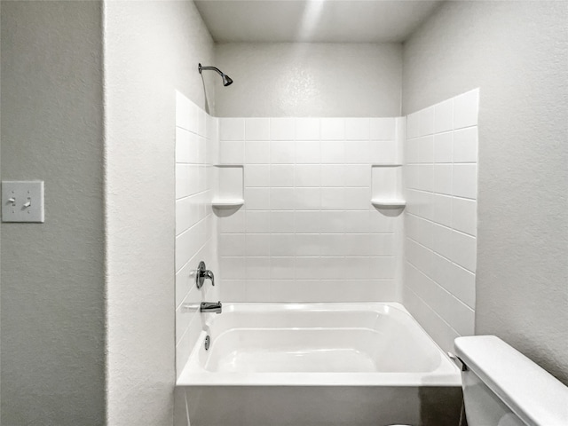 bathroom featuring tiled shower / bath combo and toilet