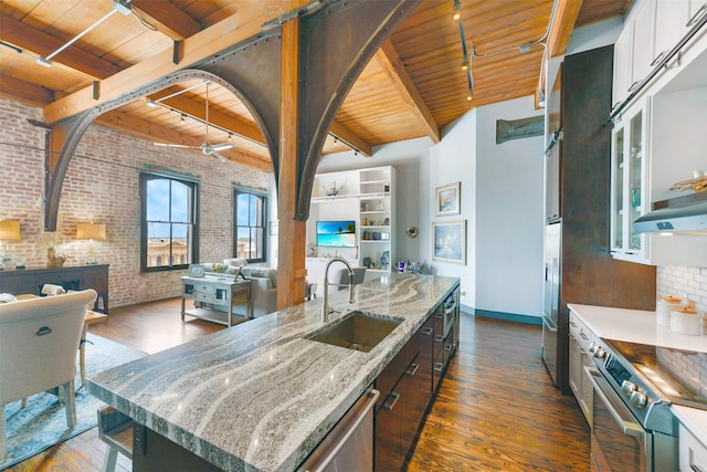 kitchen featuring light stone countertops, sink, an island with sink, and wood ceiling