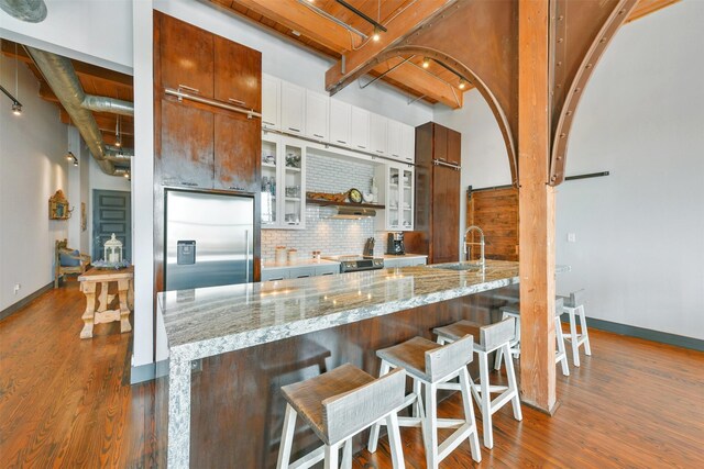 kitchen featuring white cabinetry, a breakfast bar, built in fridge, tasteful backsplash, and dark hardwood / wood-style floors