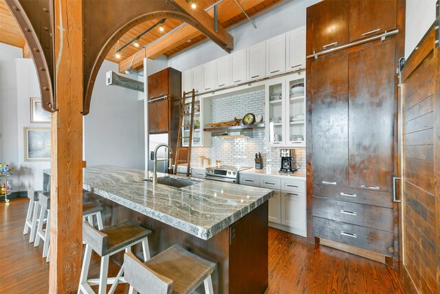 kitchen with sink, a breakfast bar, dark hardwood / wood-style floors, electric range, and white cabinets