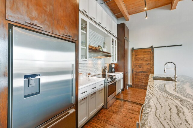 kitchen with sink, white cabinetry, stainless steel appliances, a barn door, and hardwood / wood-style flooring