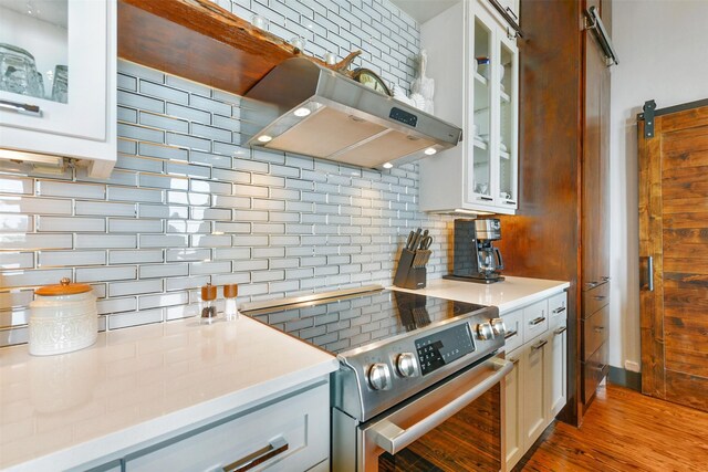 kitchen featuring stainless steel electric range oven, light hardwood / wood-style flooring, exhaust hood, white cabinetry, and tasteful backsplash