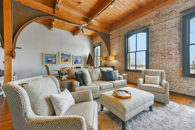 living room featuring rail lighting, dark hardwood / wood-style floors, wooden ceiling, brick wall, and beam ceiling