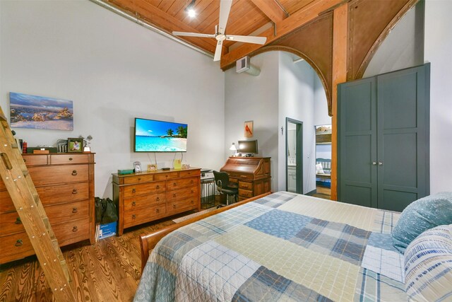 bedroom featuring beam ceiling, wood ceiling, a towering ceiling, and hardwood / wood-style floors