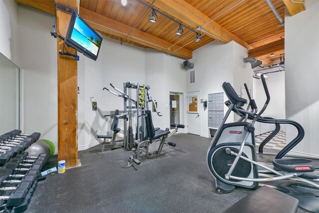 exercise room featuring rail lighting and wood ceiling