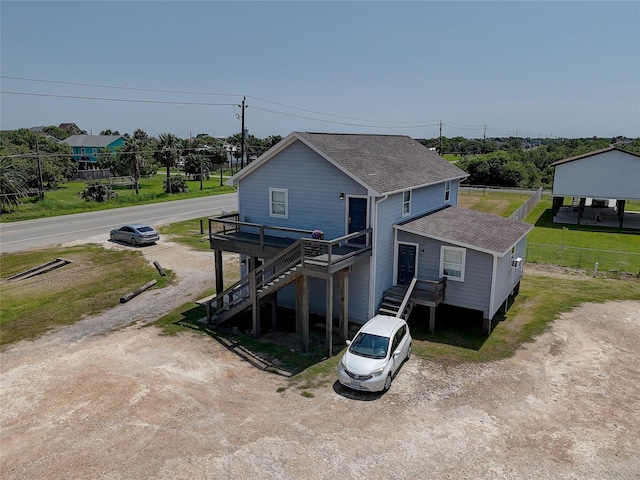 back of property featuring driveway, fence, stairway, and roof with shingles