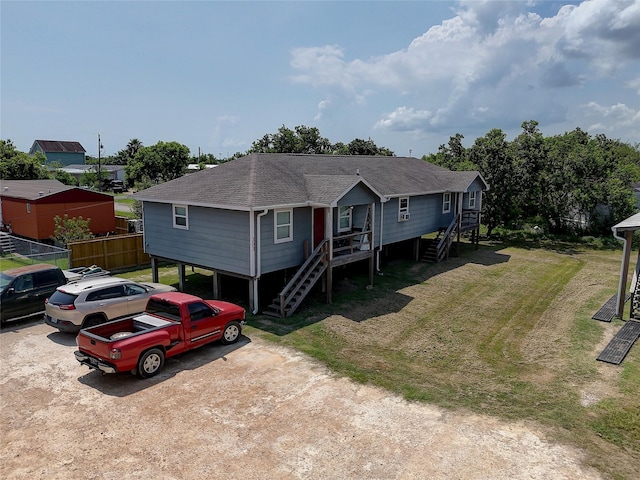 view of front of home with a shingled roof, fence, stairs, driveway, and a front lawn