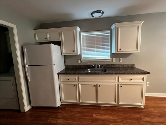 kitchen with dark wood-type flooring, freestanding refrigerator, washer / clothes dryer, and a sink