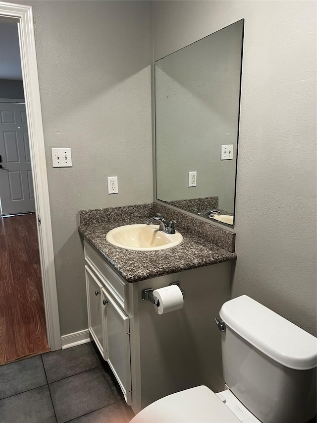 half bath with tile patterned flooring, vanity, and toilet