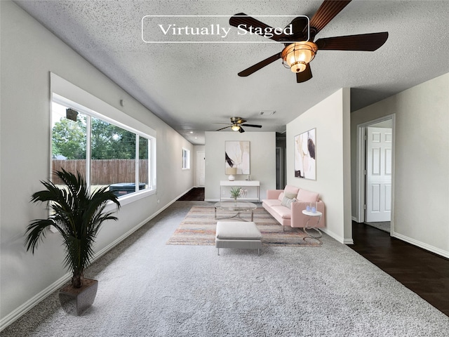 living room featuring dark wood-type flooring, a textured ceiling, and ceiling fan