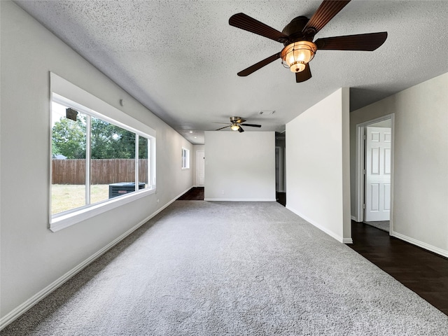 unfurnished living room with dark colored carpet, a textured ceiling, and ceiling fan