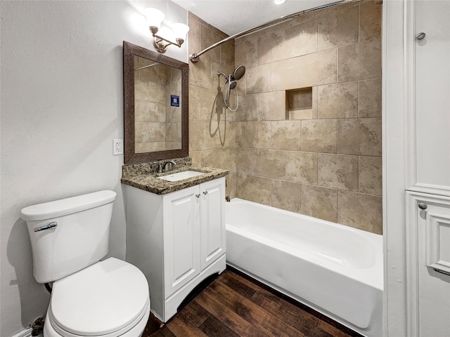 full bathroom featuring tiled shower / bath, a textured ceiling, toilet, vanity, and wood-type flooring